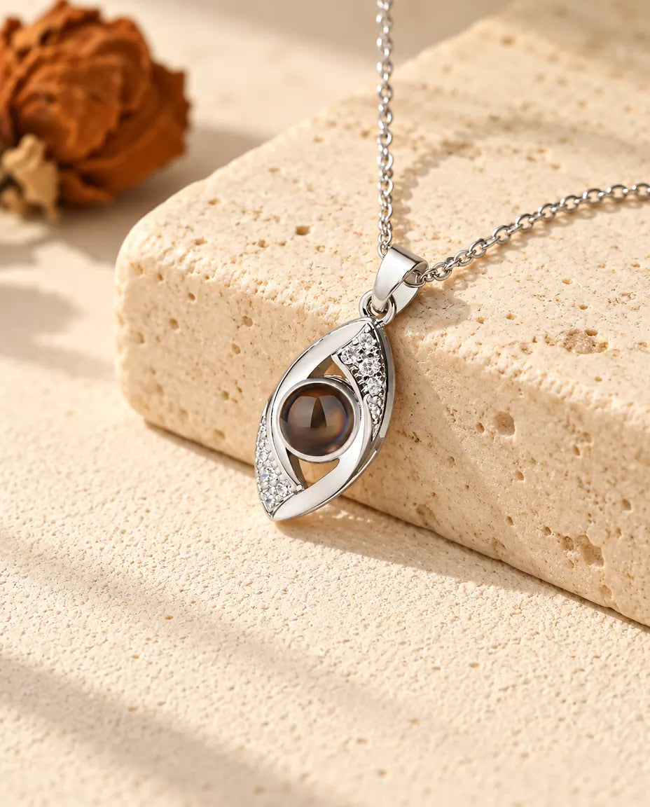 Gepersonaliseerde zilverkleurige ketting met foto erin in de vorm van het boze oog op travertijn
