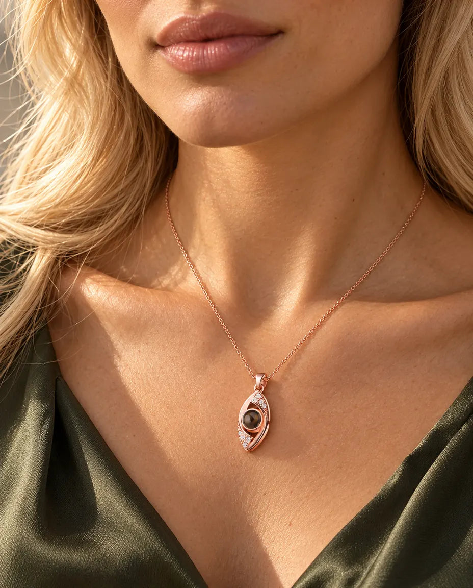 Vrouw in een olijfgroene top draagt de roségoudkleurige ketting met het boze oog