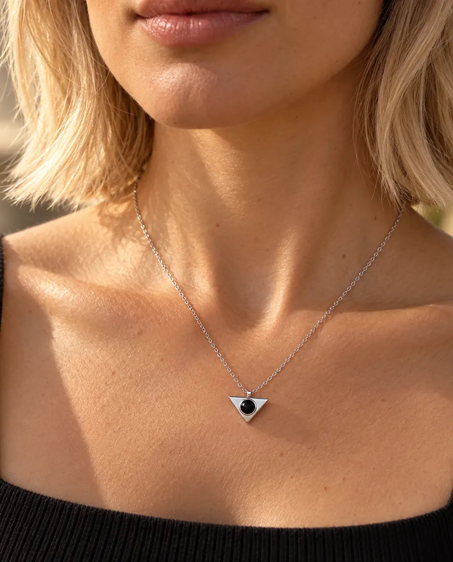 Vrouw in een zwarte top draagt de minimalistische zilverkleurige ketting met driehoek