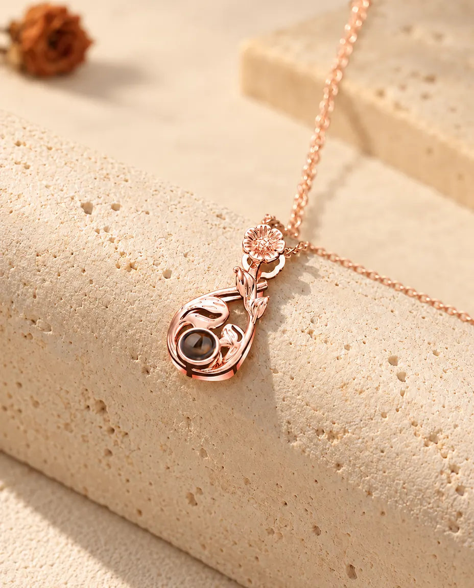 Roségoudkleurige ketting met bloemendruppel en foto erin, hangend over travertijn
