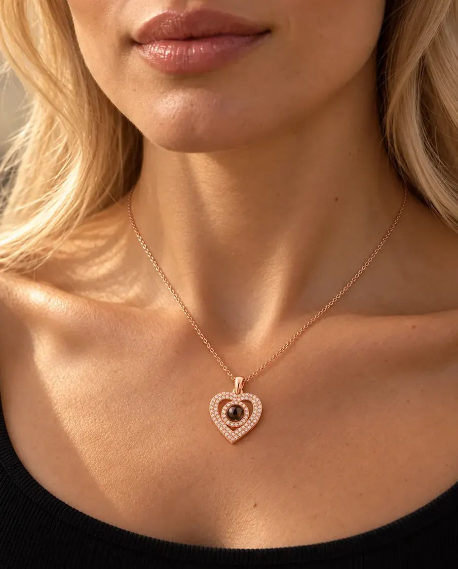 Vrouw in een zwarte gebreide top draagt de roségoudkleurige ketting met dubbel hart en foto erin