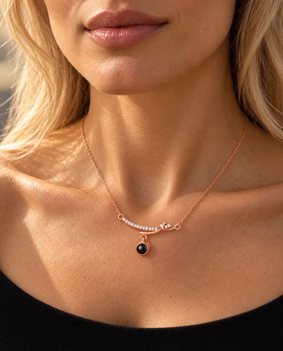 Vrouw in een zwarte top draagt de roségoudkleurige ketting met gebogen staafje bij het sleutelbeen