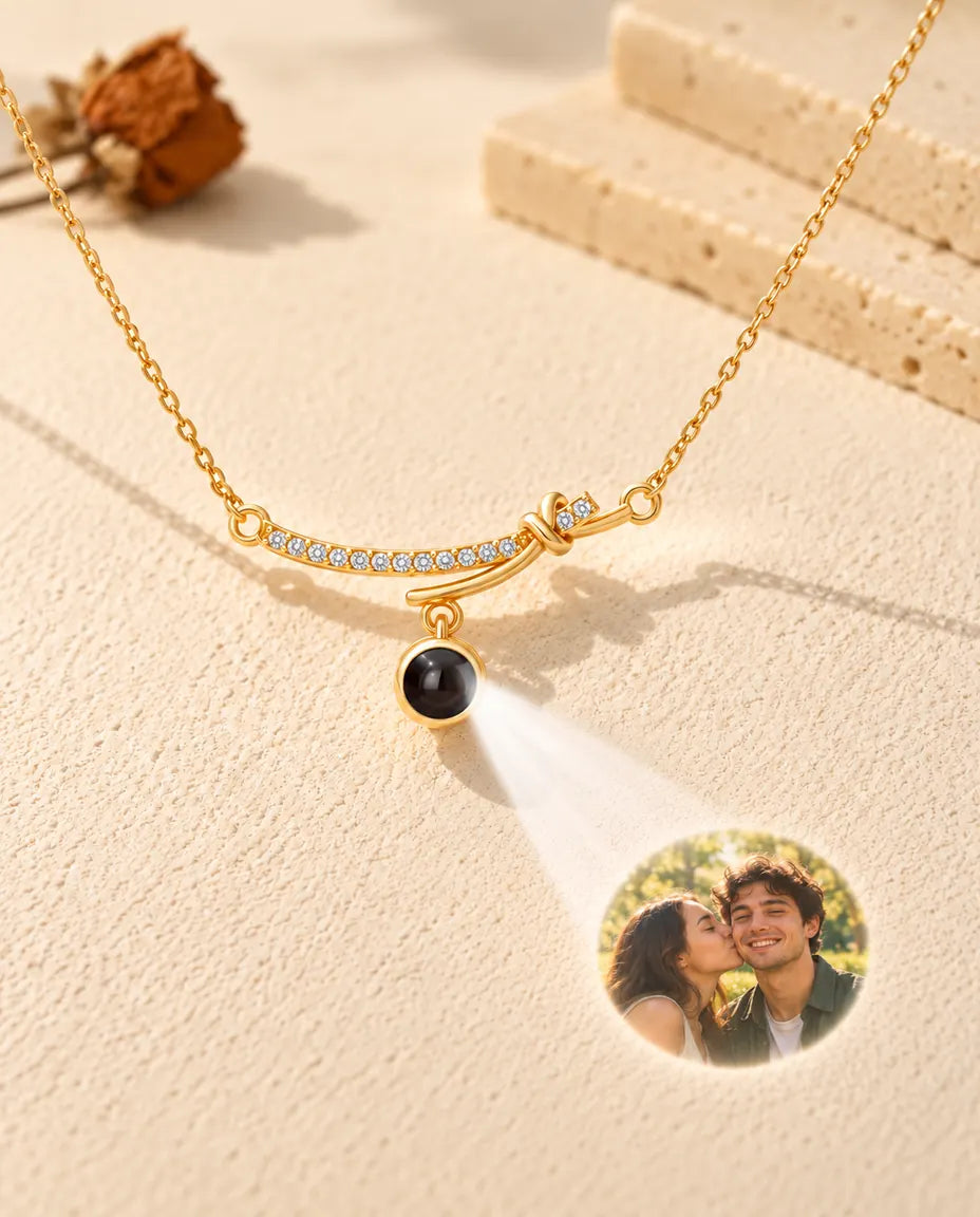 Goudkleurige ketting met gebogen staafje projecteert een foto van een stel op crèmekleurig gips