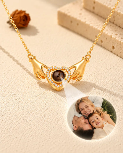 Licht door het bruine steentje van de goudkleurige ketting met handjes en hart toont een familiefoto