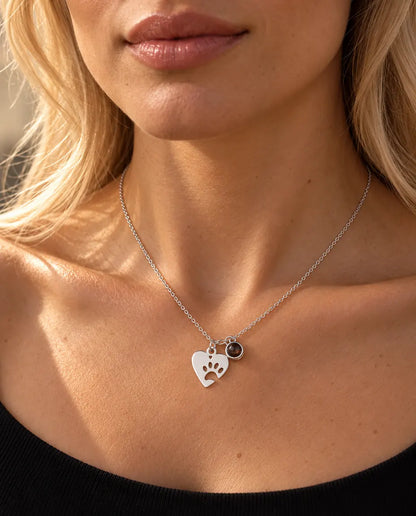 Vrouw in een zwarte gebreide top draagt de zilverkleurige ketting met pootjeshart en foto van haar huisdier