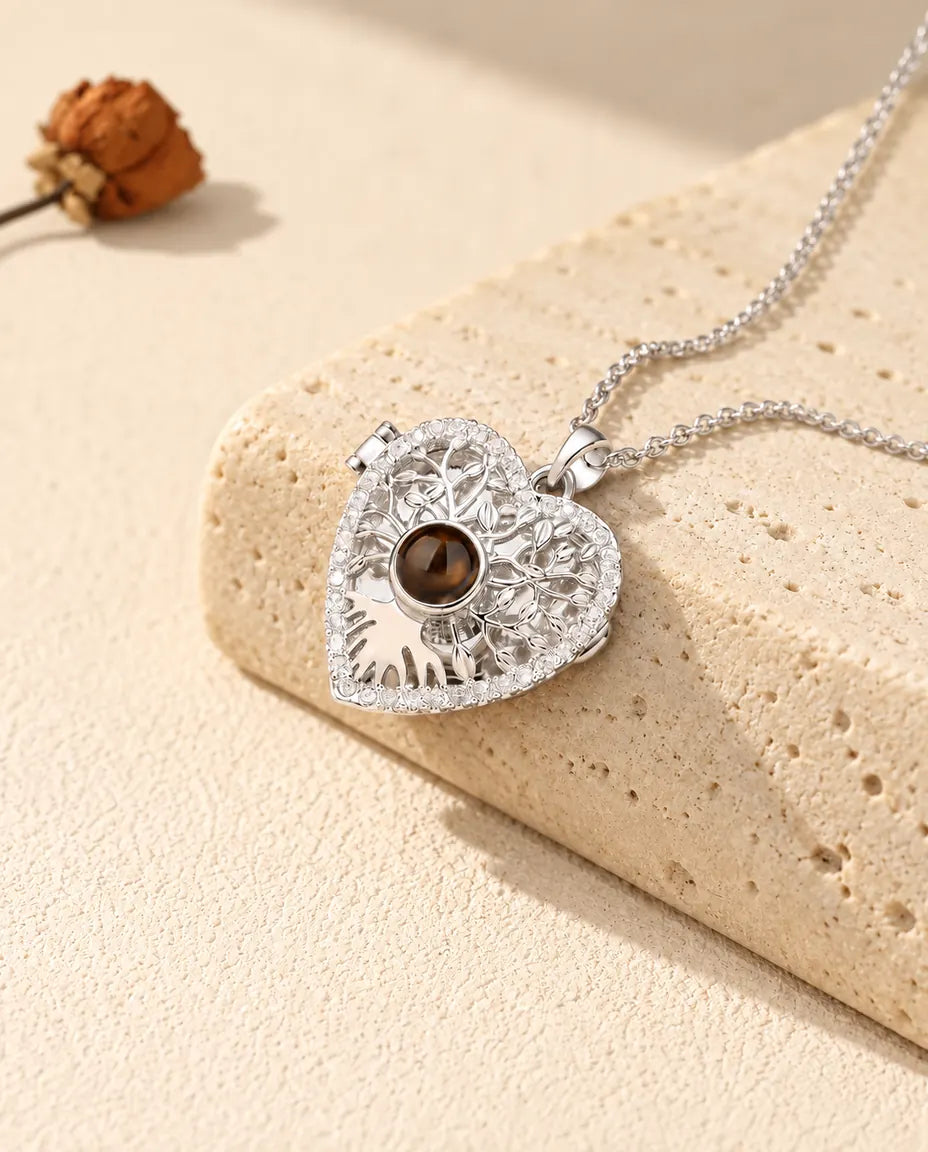 Gepersonaliseerde zilverkleurige ketting met hartmedaillon, levensboom en bruin projectiesteentje op een travertijnblok
