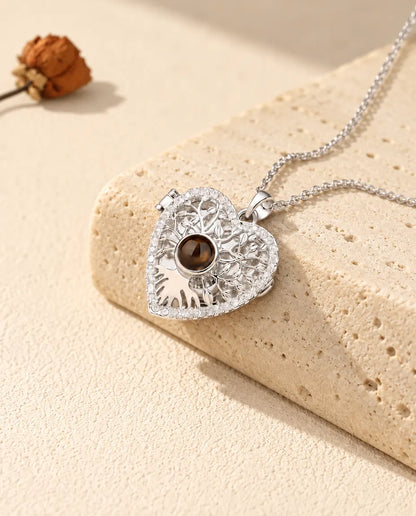 Gepersonaliseerde zilverkleurige ketting met hartmedaillon, levensboom en bruin projectiesteentje op een travertijnblok