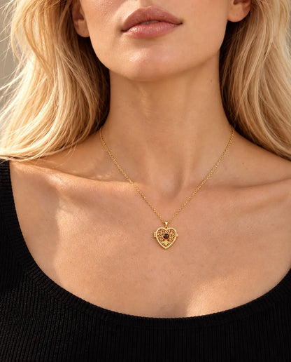 Blonde vrouw in een zwarte top draagt de goudkleurige ketting met hartmedaillon, levensboom en projectiesteentje
