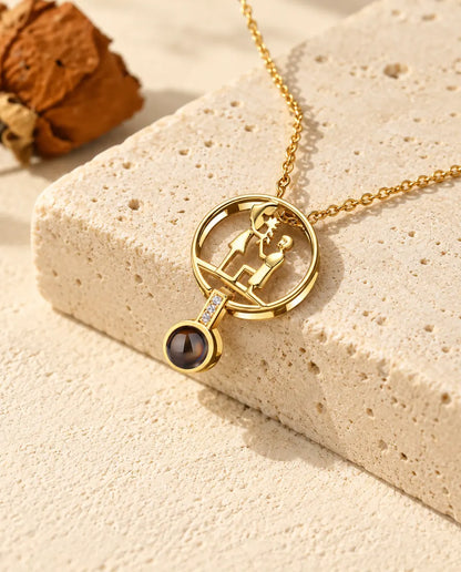 Gepersonaliseerde goudkleurige ketting met foto erin en een geknield stel op travertijn