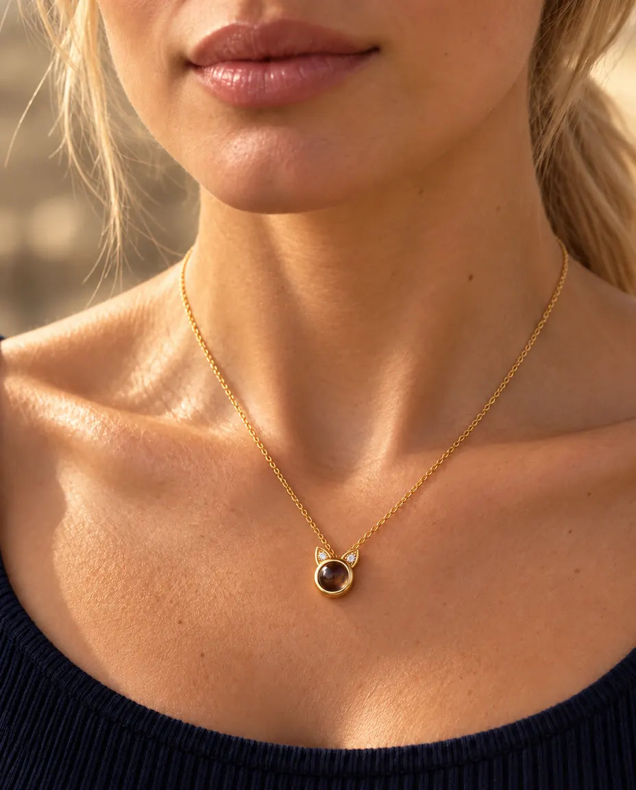 Vrouw in een marineblauwe top draagt de kleine goudkleurige ketting met kattenoortjes
