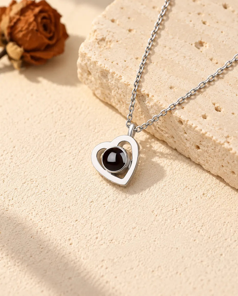 Gepersonaliseerde ketting met foto erin van 925 sterling zilver: dubbel hartje op crèmekleurig gips naast travertin
