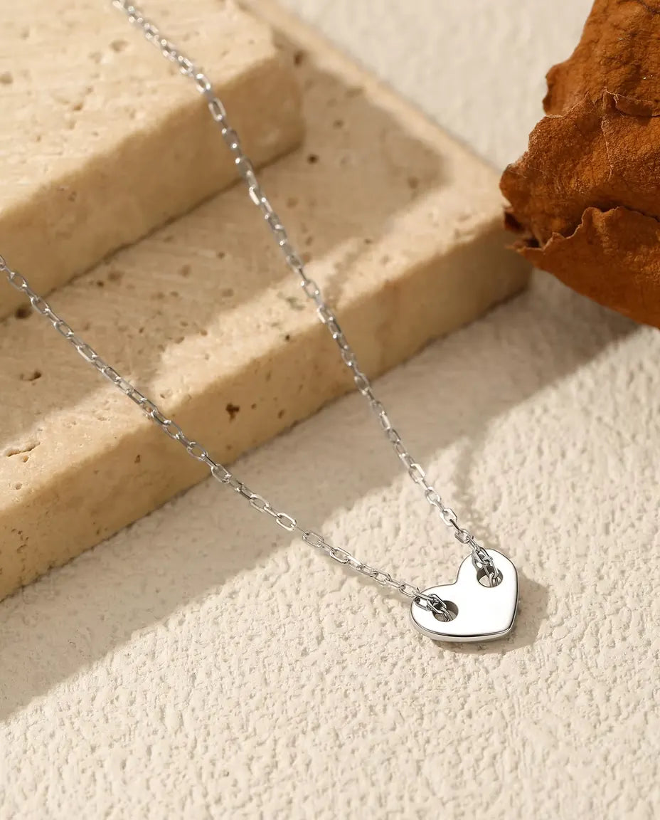 Ketting met Hartje in 925 Sterling Zilver - hanger op een licht oppervlak naast een travertijnplaat