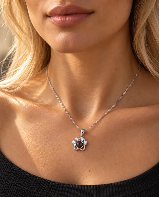 Vrouw in een antracietgrijze gebreide top draagt de zilverkleurige ketting met pootje