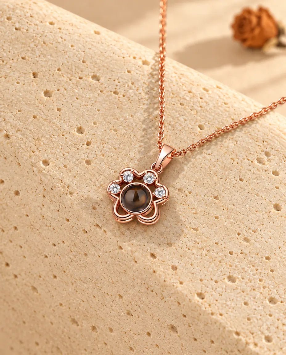 Roségoudkleurige ketting met pootje en foto erin over travertijn gedrapeerd