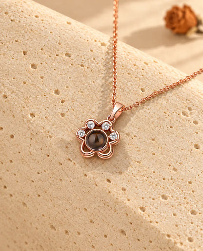 Roségoudkleurige ketting met pootje en foto erin over travertijn gedrapeerd