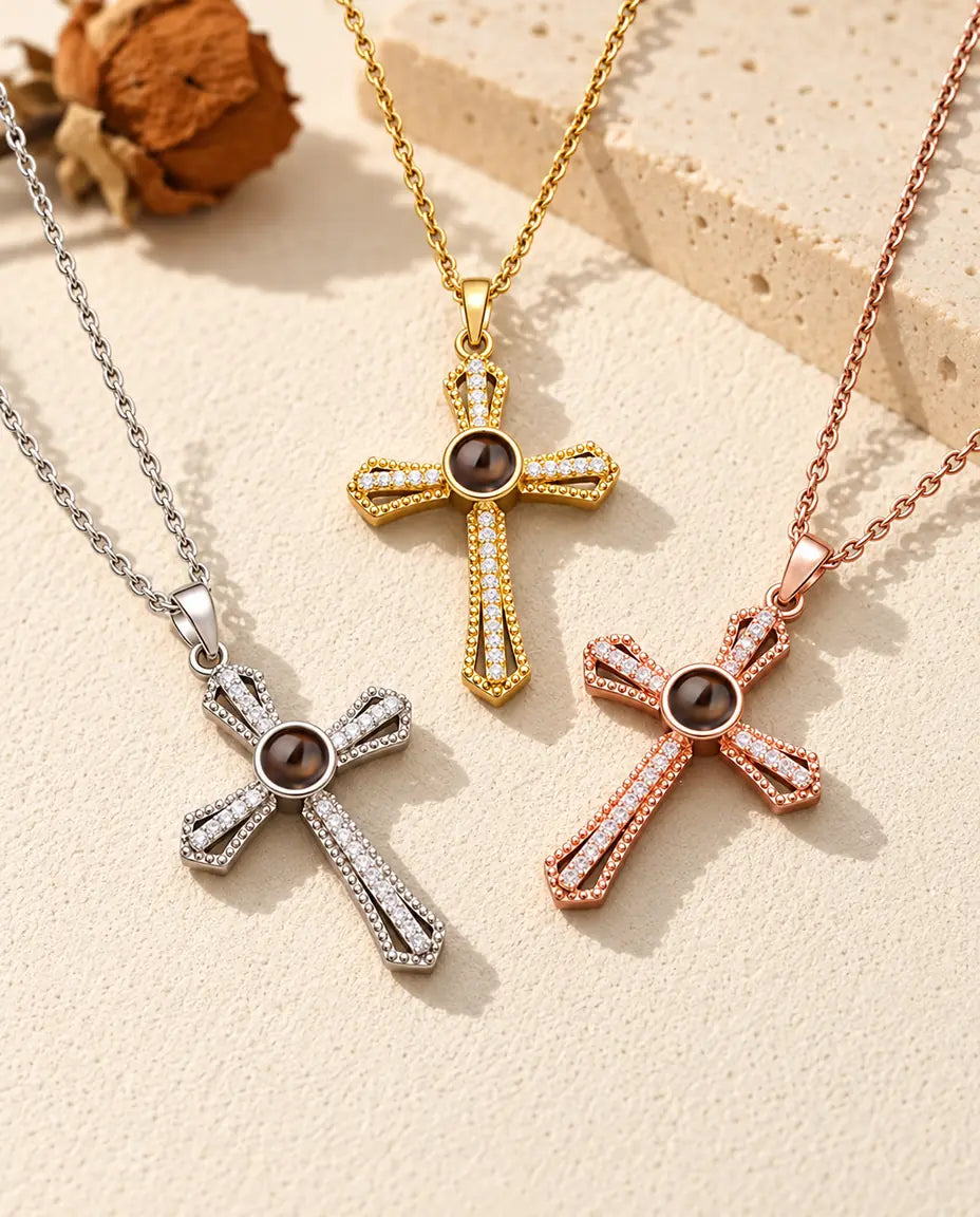 De ketting met kruis en foto erin in drie kleuren uitgespreid op crèmekleurig gips