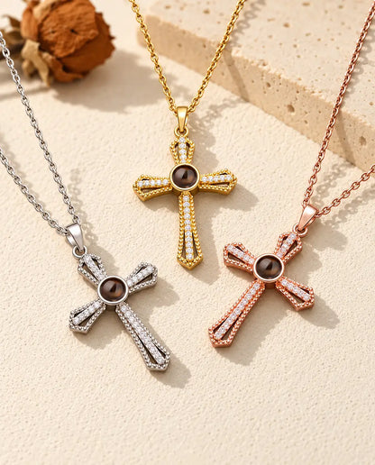 De ketting met kruis en foto erin in drie kleuren uitgespreid op crèmekleurig gips