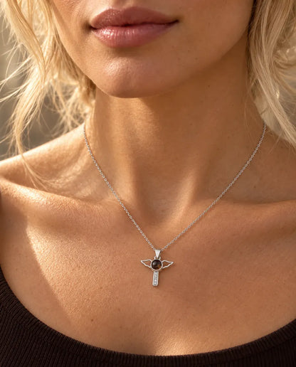 Vrouw in een bruine top draagt de zilverkleurige ketting met kruisje en engelenvleugels