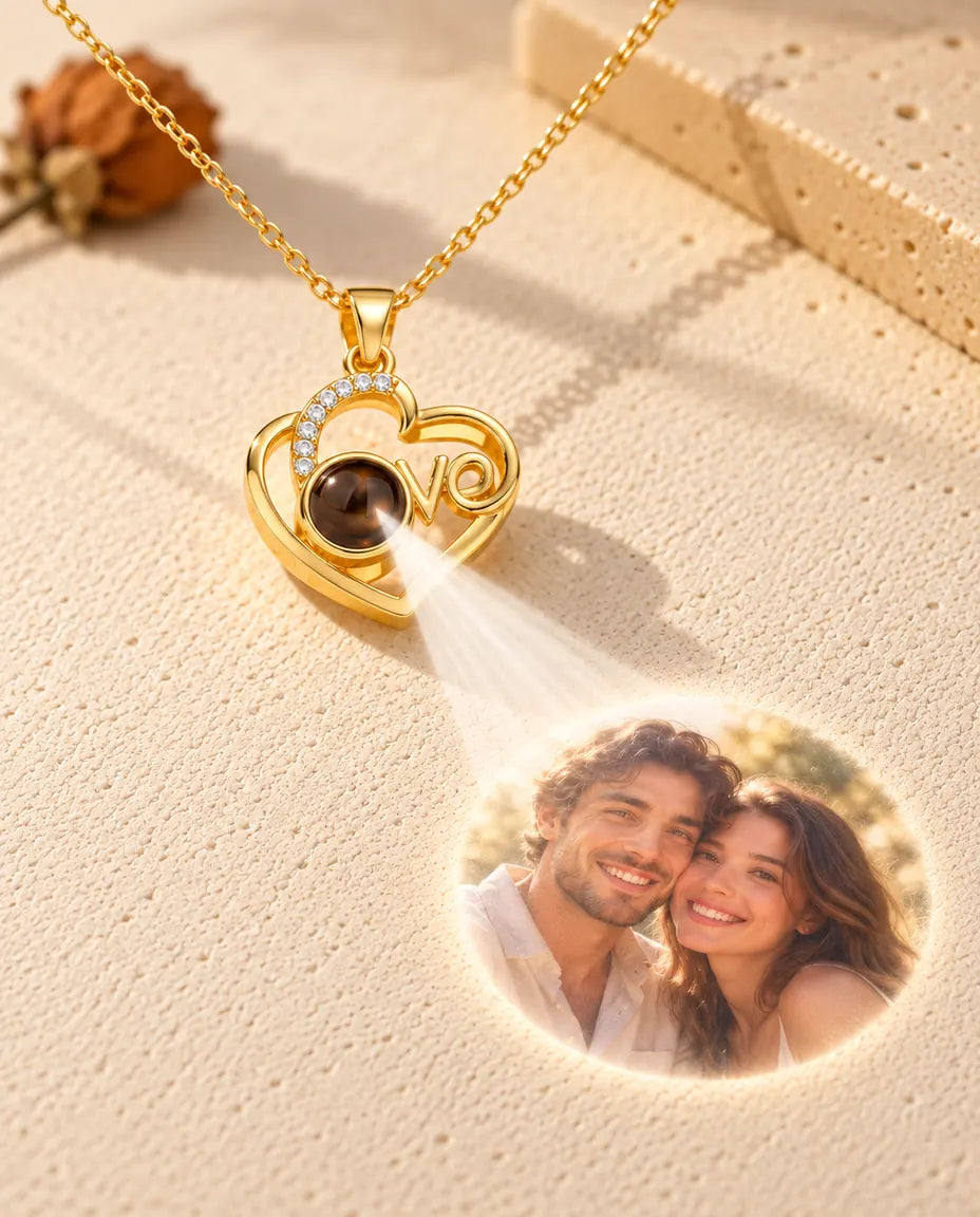 Goudkleurige Love-hart ketting projecteert een foto van een stel vanuit het steentje op crèmekleurig gips