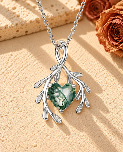 Mosagaat Ketting Hart met Takjes in 925 Sterling Zilver - liggend op een licht gestructureerd oppervlak naast een blok travertijn
