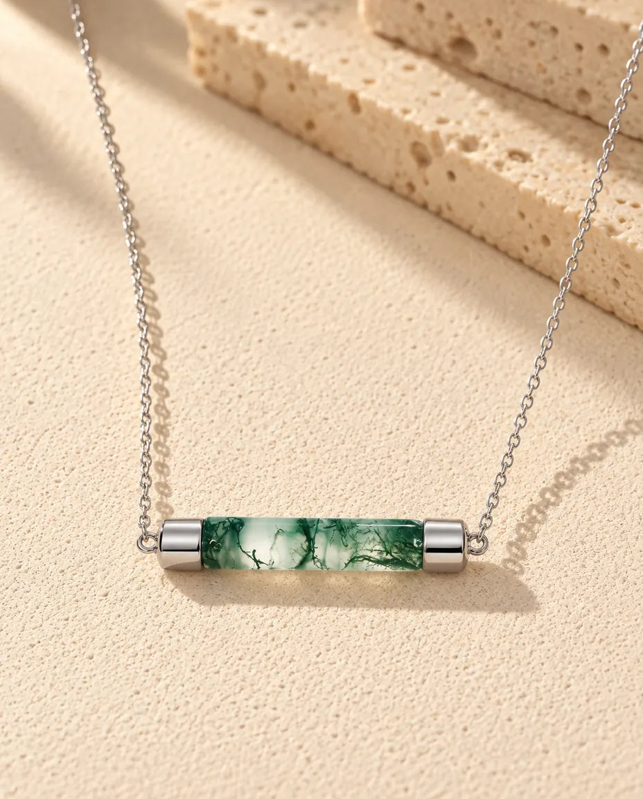 Mosagaat Ketting met Staafje in 925 Sterling Zilver - liggend op een licht gestructureerd oppervlak naast een blok travertijn
