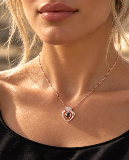 Vrouw in een zwarte top draagt de roségoudkleurige ketting met open hart en foto erin