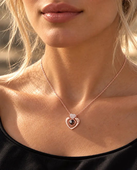 Vrouw in een zwarte top draagt de roségoudkleurige ketting met open hart en foto erin