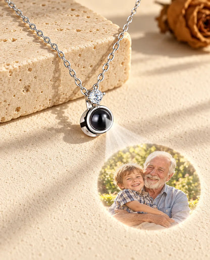 Zilverkleurige ketting met solitair projecteert een foto van opa en kleinzoon op gips