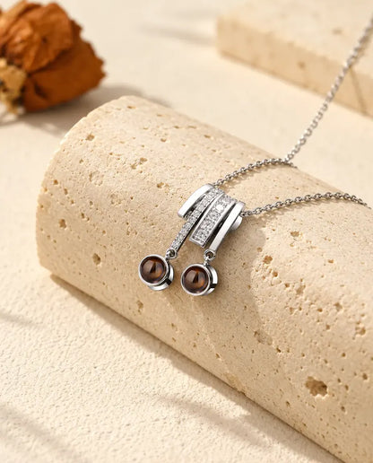 Gepersonaliseerde zilverkleurige ketting met twee foto's: schuifhanger met zirkonia en twee bruine steentjes op travertijn