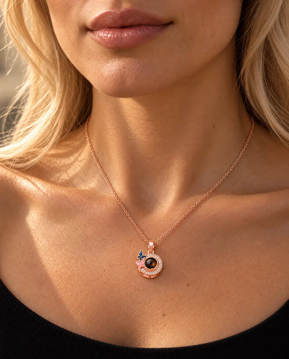 Vrouw in een zwarte gebreide top draagt de roségoudkleurige ketting met vlindertjes en foto erin