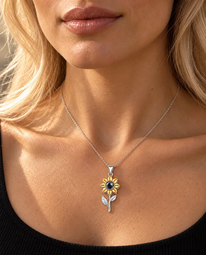 Vrouw in een zwarte top draagt de zilveren ketting met een zonnebloem aan een steeltje