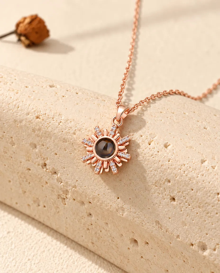 Roségoudkleurige ketting met zonnetje en foto erin, hangend over travertijn