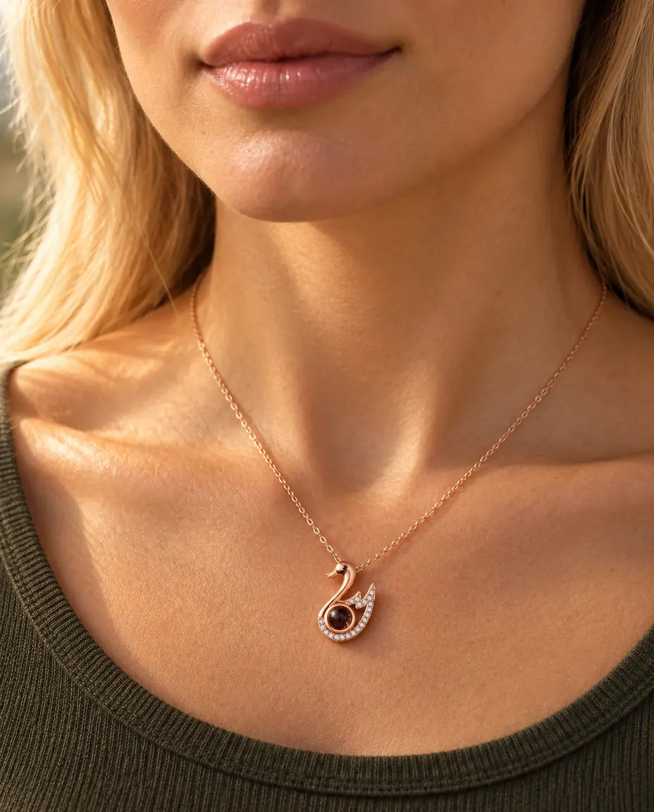 Vrouw in een olijfgroene gebreide top draagt de roségoudkleurige ketting met zwaan