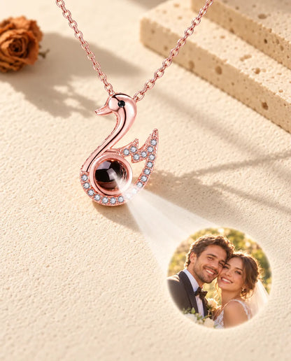 Roségoudkleurige zwaan projecteert een trouwfoto op crèmekleurig gips, met de ketting ervoor