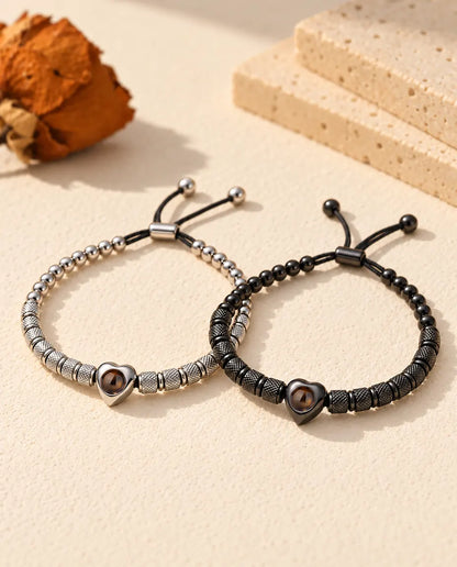 Koppel armbanden met foto erin: set van twee kralenarmbanden met hartkraal, zilverkleurig en zwart, op gips
