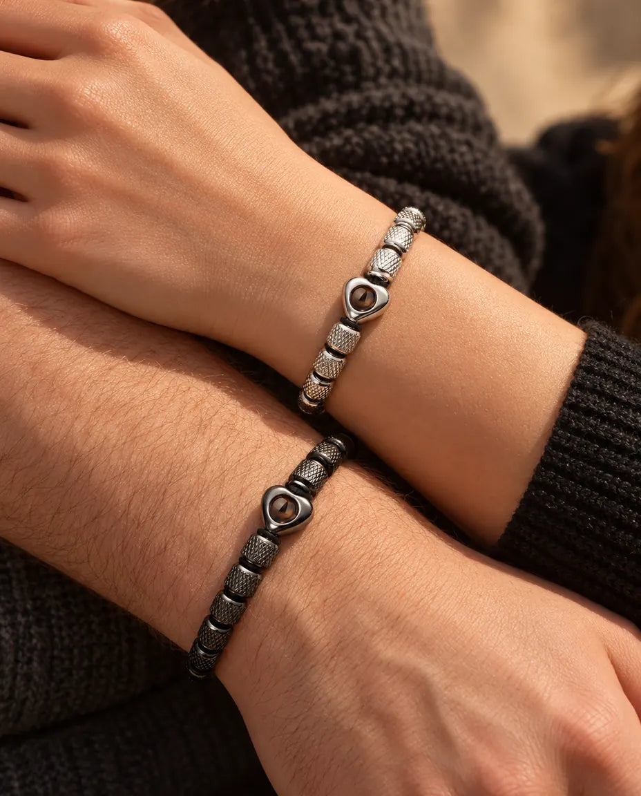 Close-up van zijn en haar pols naast elkaar met de zilverkleurige en zwarte armbanden met hartkraal