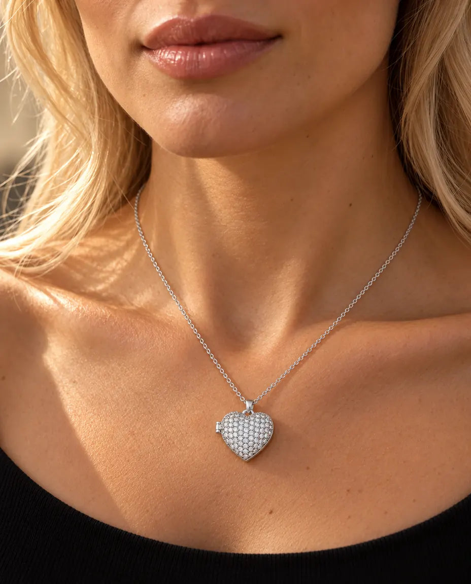 Vrouw in een zwarte gebreide top draagt de ketting met het zilverkleurige pavé hartmedaillon