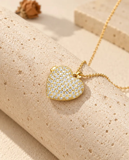Ketting met een goudkleurig pavé hartmedaillon, liggend op een blok travertin