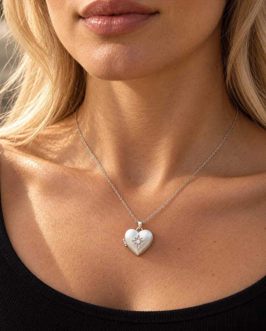 Vrouw in een zwarte gebreide top draagt de ketting met het zilverkleurige gesatineerde hartmedaillon