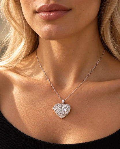 Vrouw in een zwarte gebreide top draagt de zilverkleurige ketting met hartmedaillon met engelenvleugel en poot