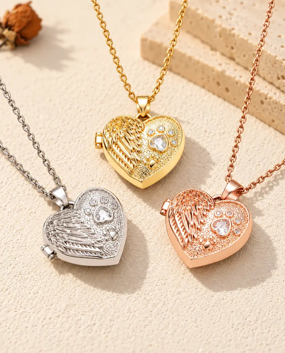 De drie kleuren van de ketting met hartmedaillon met engelenvleugel en poot samen uitgestald op gips