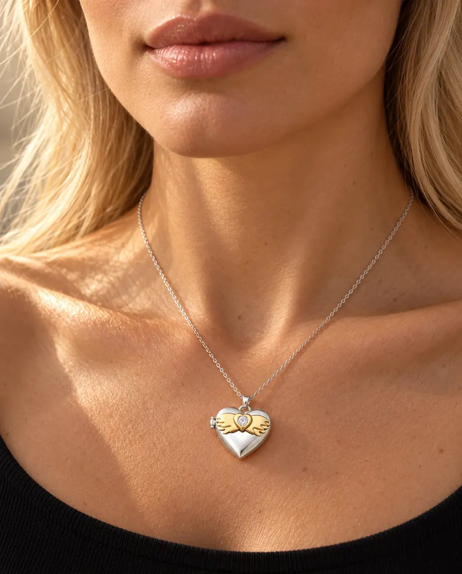 Vrouw in een zwarte gebreide top draagt de ketting met het zilverkleurige hartmedaillon met vleugels