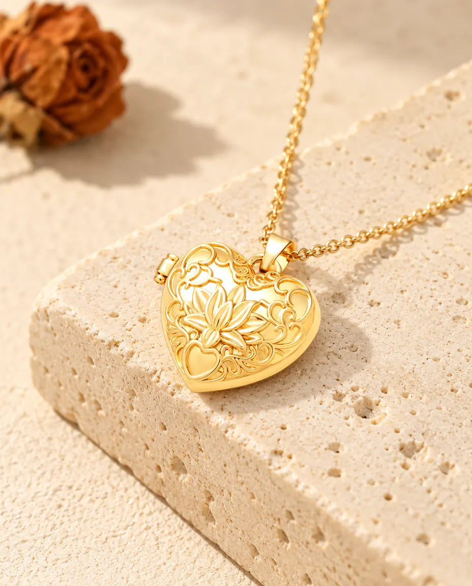 Goudkleurige ketting met hartmedaillon met lotusbloem, neergelegd op een blok travertin