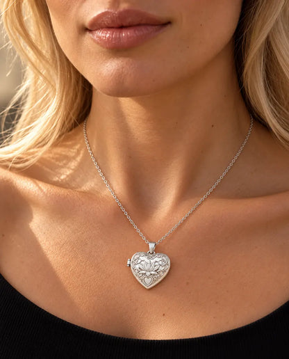 Vrouw in een zwarte gebreide top draagt de zilverkleurige ketting met hartmedaillon met lotusbloem