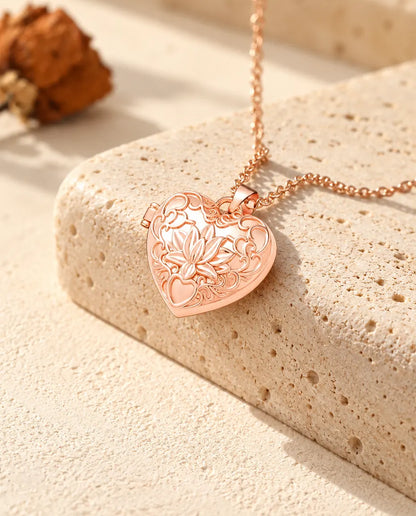 Roségoudkleurige ketting met hartmedaillon met lotusbloem op travertin in warm zonlicht
