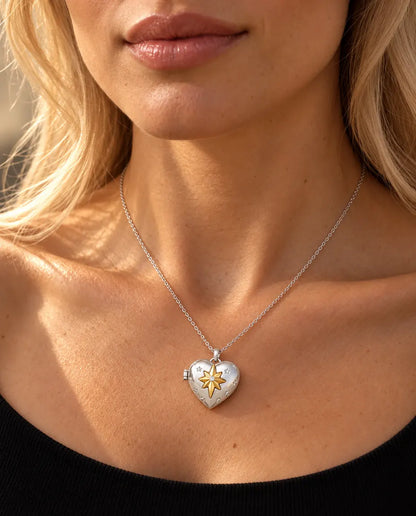 Vrouw in een zwarte gebreide top draagt de ketting met het zilverkleurige hartmedaillon met poolster