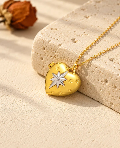 Ketting met een goudkleurig hartmedaillon met poolster, liggend op een blok travertin