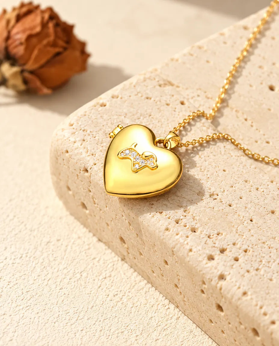 Ketting met een goudkleurig hartmedaillon met puppy, liggend op een blok travertin