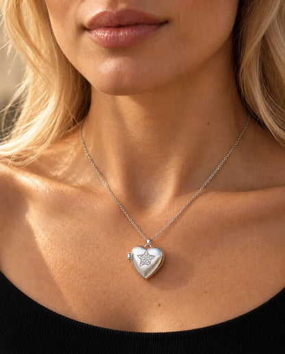 Vrouw in een zwarte gebreide top draagt de ketting met het zilverkleurige hartmedaillon met ster