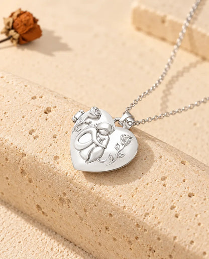 Hartvormig medaillon met foto, vrouw met hond tussen twee rozen in reliëf, zilverkleurig, tegen een blok travertin